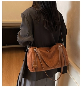 Detail of caramel brown suede Boston bag showing leather strap and metallic side buckle