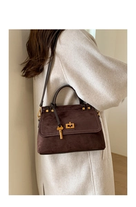 Detail of dark brown faux suede crossbody bag with gold key pendant and metal twist lock
