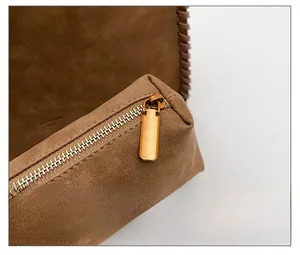 Macro shot of smooth bronze metal zipper on textured brown soft leather shoulder bag
