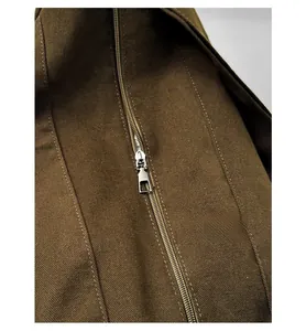 Detail shot of a smooth silver metal zipper on premium brown twill canvas fabric