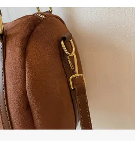 Detail of premium golden hardware and brown suede material on a crossbody bag