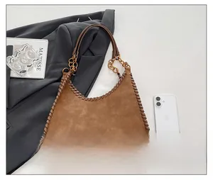 Detail of brown suede shoulder bag featuring hand-woven leather edges and chain strap