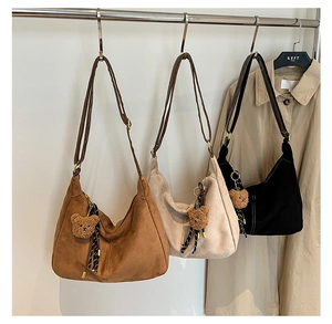 Dettaglio delle borse a mezzaluna in camoscio color caramello, beige e nero con cuciture