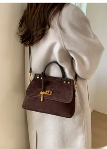 Detail of vintage brown suede crossbody bag featuring gold lock and key charm