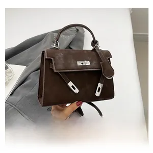 Detail of dark brown suede handbag with silver turn-lock and vintage textured finish