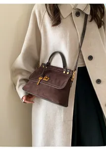 Detail of vintage brown suede handbag with golden square lock and key pendant on model