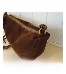Detailed close-up of dark brown suede texture and golden ring hardware on the bag