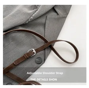 Detail of an adjustable brown leather strap with silver buckle on a grey suit