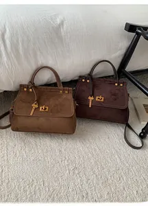 Detailed view of vintage suede handbags in camel and coffee brown with gold hardware