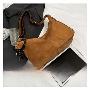 Dettaglio borsa tote in pelle scamosciata marrone con ciondolo a orso e cordino decorativo
