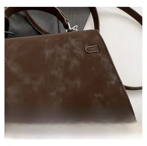 Detail view of coffee brown crossbody bag showing vintage matte leather texture and strap