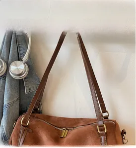 Detail of dark brown suede shoulder bag with golden hardware and leather straps