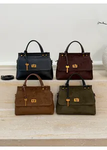 Macro shot of retro suede handbags in four colors featuring golden turn-lock and key charms