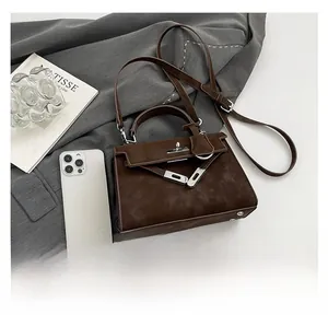 Close-up of brown matte texture handbag with silver hardware and Kelly buckle detail