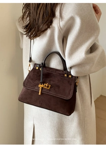 Detail of vintage dark brown faux suede handbag with gold clasp and elegant key pendant