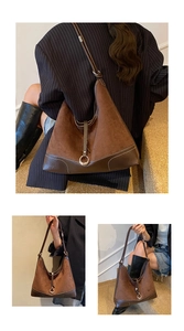 Bruine suède hobo-tas met lederen patchwork en metalen ring gedragen door een model