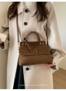 Detail of dark brown frosted leather handbag with golden twist lock and flap design