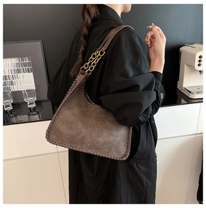 Detail of vintage shoulder bag with woven edge stitching and gold chain strap on model