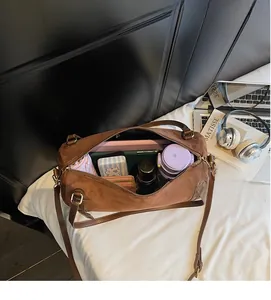 Top-down view showing the spacious interior of the brown suede Boston bag with daily items