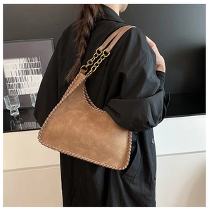 Close-up of vintage brown shoulder bag showing coarse stitching and gold chain detail