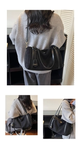 Detail of black suede Boston bag showing gold zipper and premium leather tag accessory