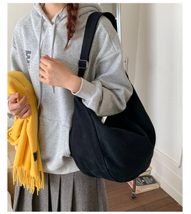 Detailed side view of a large black canvas dumpling bag worn by a model in casual attire