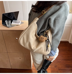 Detail of beige suede hobo bag with brown leather strap and cute bear charm pendant