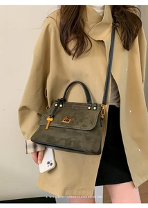 Retro moss green suede handbag with black leather accents and gold hardware on a beige trench coat