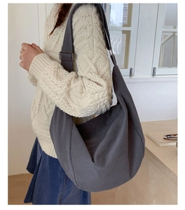 Detail of charcoal grey canvas crescent bag with adjustable wide shoulder strap on model