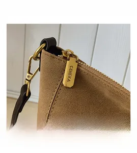 Macro shot of polished bronze hardware zipper pull and metal hook on suede tote bag