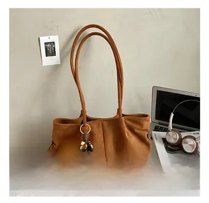 Sac cabas en daim marron avec pendentif en bois dans un décor de bureau minimaliste