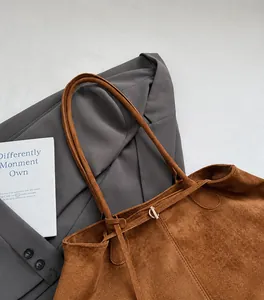 Detail van de bruine suède tote bag met slanke schouderriem en metalen sluiting luxe