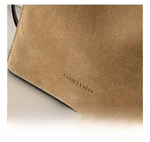 Close-up of CAHRES & HEKA logo on premium matte brown suede tote bag with fine texture
