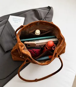 Gedetailleerd interieur van grote bruine suède shopper met vakken en ruime inhoud