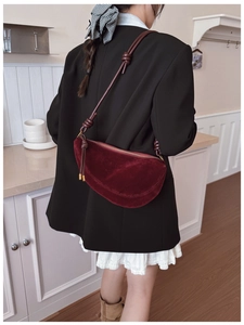 Close-up of deep burgundy suede half-moon bag with elegant knotted strap detail