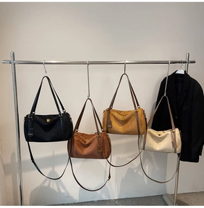 Four colors of cylinder boston bags in matte suede texture hanging on metal hangers
