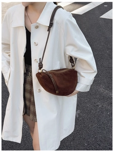 Close-up of brown suede half-moon bag with knotted shoulder strap and zipper detail