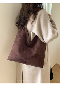 Detail der minimalistischen dunkelbraunen matten Wildleder-Tote-Bag mit weißem Wollmantel