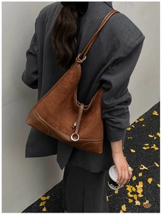 Detail of brown suede tote bag with contrast stitching and silver metal ring on strap