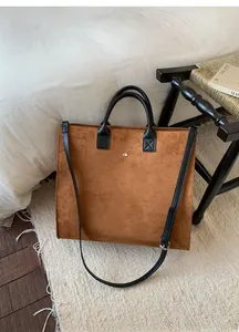 Dettaglio della borsa tote in finta pelle scamosciata marrone con manici in pelle nera