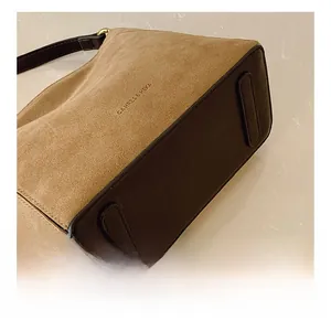 Detail shot of the suede bucket bag bottom with brown leather protective wear-resistant strips