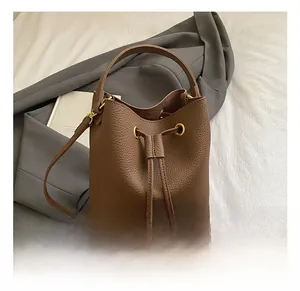 Close-up of brown pebbled leather bucket bag featuring gold hardware and drawstring detail