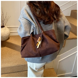 Sac cabas en daim marron avec pampille en perles de bois sur un pull gris décontracté