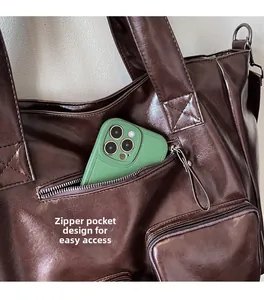 Detail shot of the front zipper pocket on a brown tote bag holding a smartphone