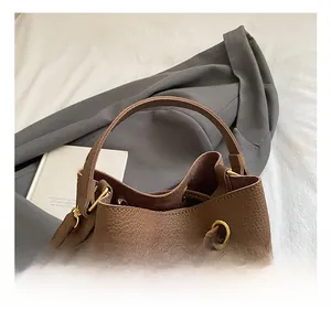 Detail of dark brown lychee grain leather bucket bag with sturdy handle and gold hardware