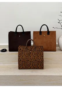 Dettaglio di grandi borse tote in tela leopardata e colori a tinta unita con fibbie metalliche