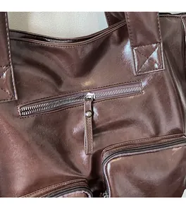 Detail of smooth metal zipper and reinforced stitching on a brown leather tote bag
