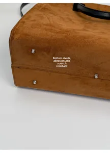 Dettaglio dei rivetti in metallo sul fondo della borsa tote in pelle scamosciata marrone