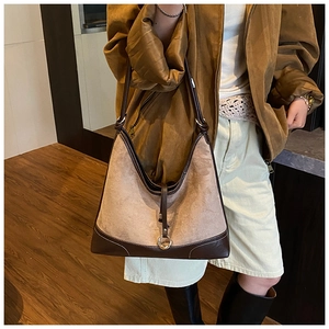 Detail of suede and brown leather patchwork hobo tote bag in a warm interior setting