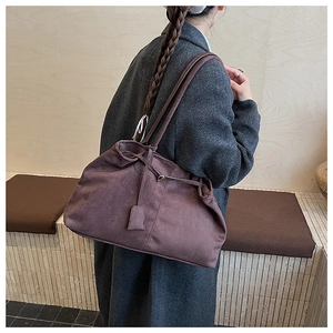 Detail of dark brown suede tote bag with drawstring closure and matte texture